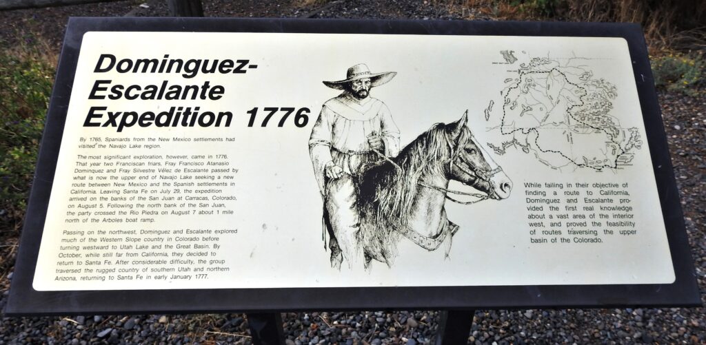 An informative sign about the Dominguez-Escalante Expedition of 1776 features text about the journey, a monochrome illustration of a man on horseback, and descriptions of the explorers' efforts to find a route to California from what is now Utah and Colorado.