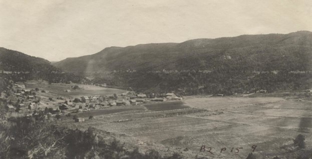 Aerial black and white photo of a rural village (Pinon, Colorado) in a valley with surrounding fields and hills.