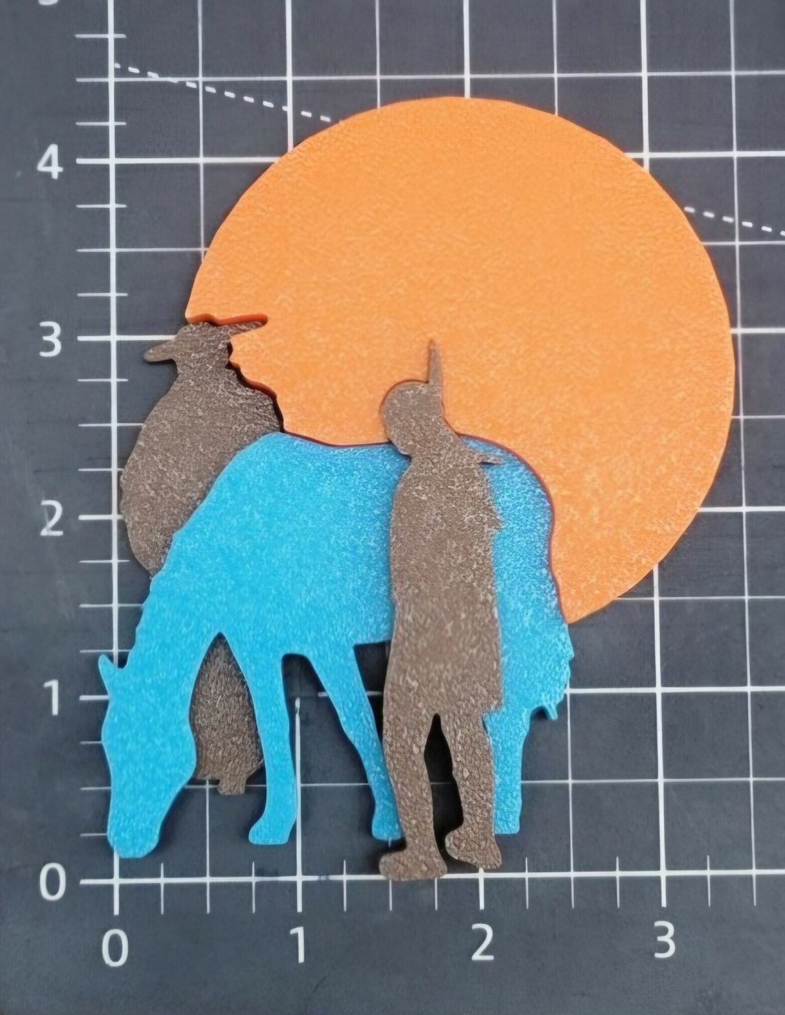 Layered 3D interlocking pieces featuring a silhouette of a Franciscan, a Native American and a horse in front of an orange circle on a black grid background.